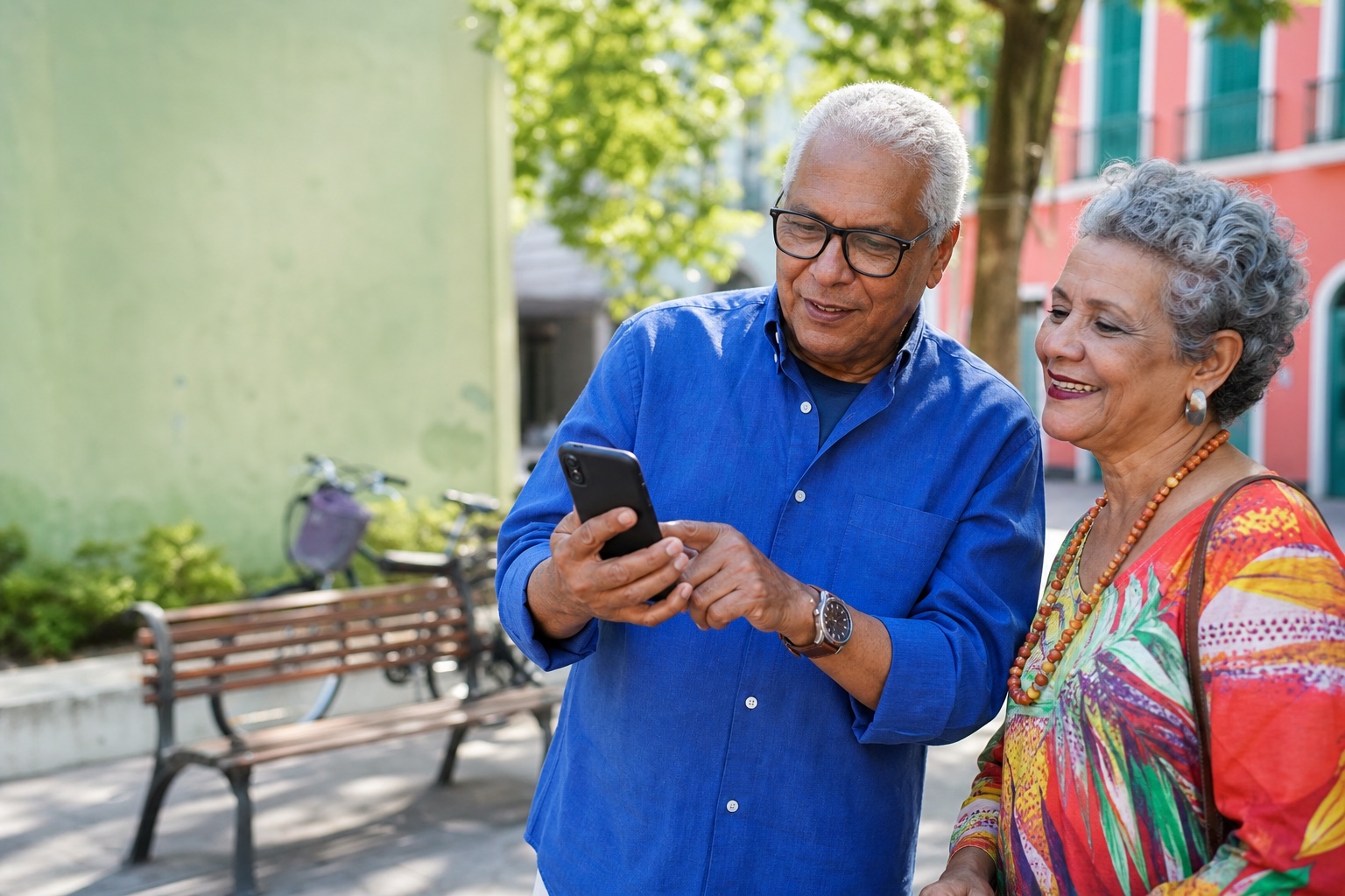 Homem e mulher idosos usam um celular juntos em uma praça ensolarada e colorida.